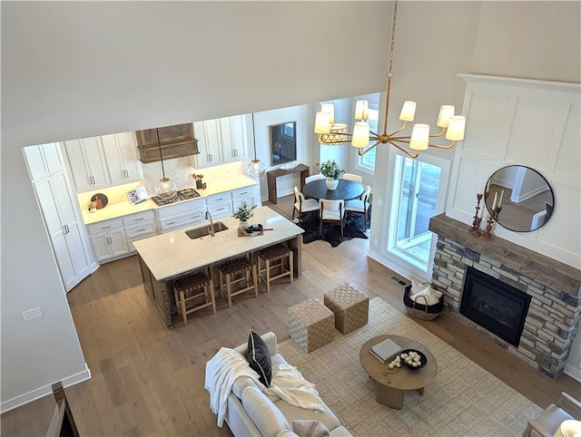 living room featuring sink, a notable chandelier, a fireplace, and hardwood / wood-style floors