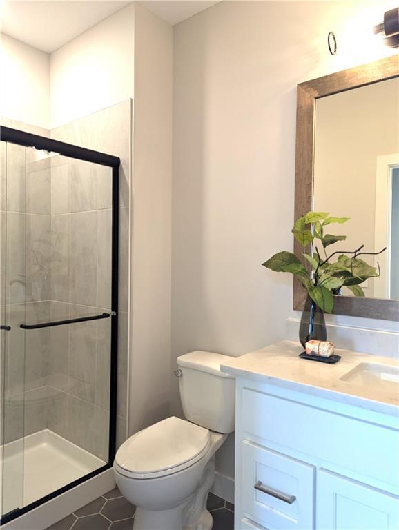 bathroom featuring an enclosed shower, vanity, tile patterned floors, and toilet