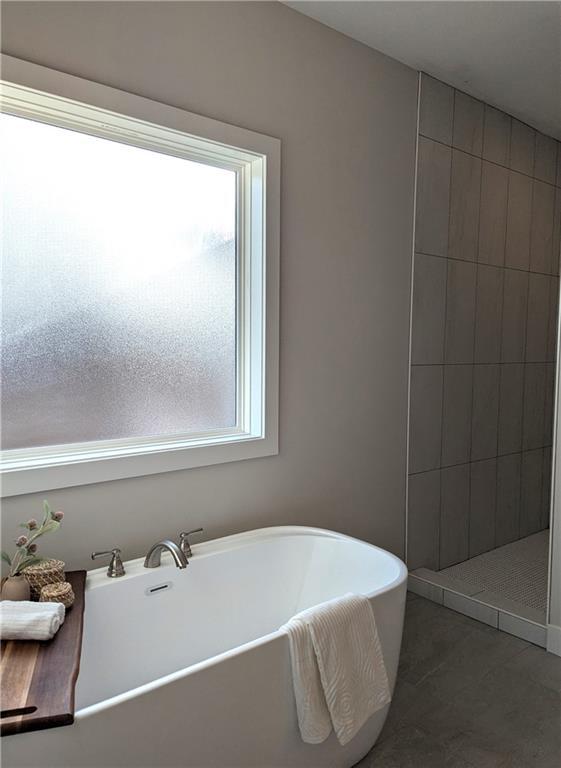 bathroom with a tub to relax in and tile patterned floors