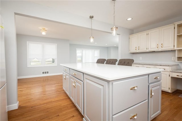 kitchen with white cabinets, light wood-type flooring, pendant lighting, and a center island