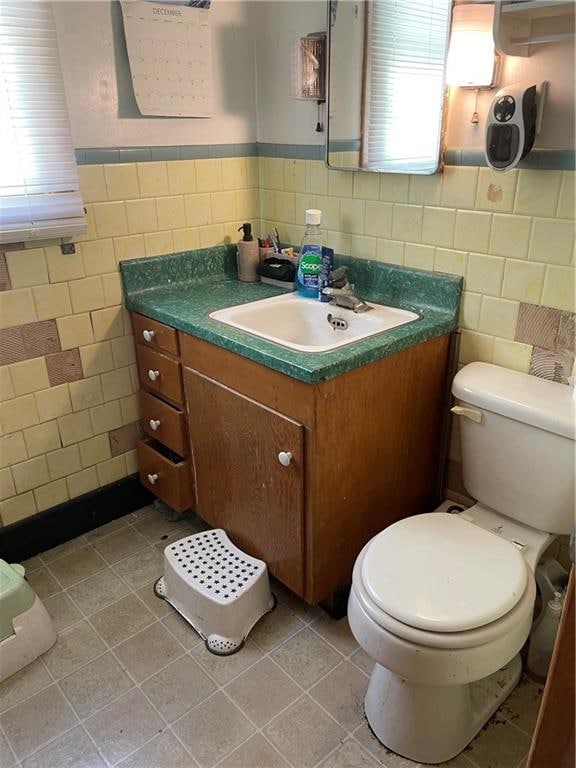 bathroom featuring tile flooring, toilet, vanity, and tile walls