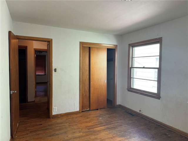 unfurnished bedroom with a closet, baseboards, and wood finished floors