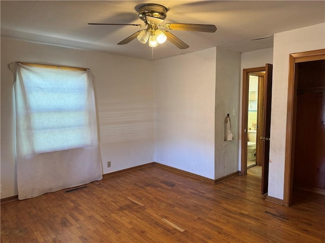 spare room with baseboards, wood finished floors, and a ceiling fan