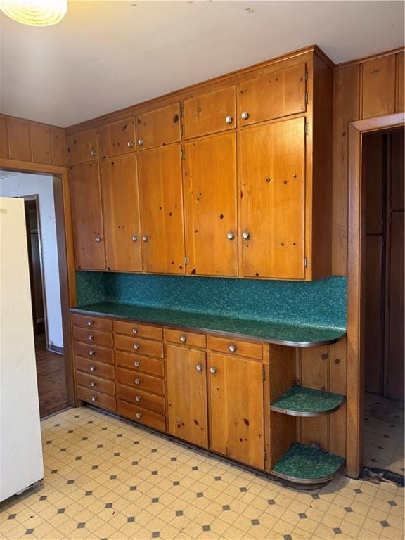 kitchen with light floors, brown cabinets, and freestanding refrigerator