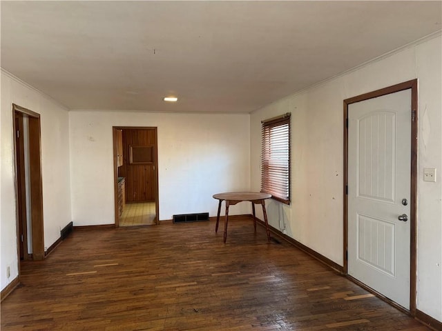 empty room featuring visible vents, crown molding, baseboards, and wood finished floors