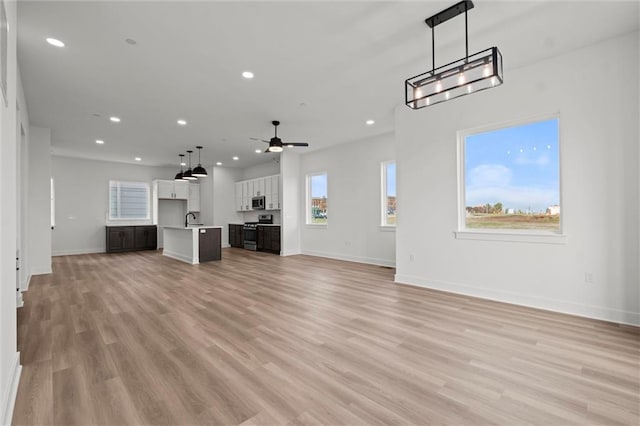 unfurnished living room featuring light hardwood / wood-style flooring, sink, and ceiling fan