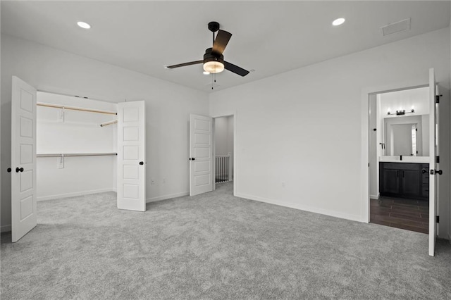 unfurnished bedroom with a closet, carpet flooring, ceiling fan, and ensuite bath