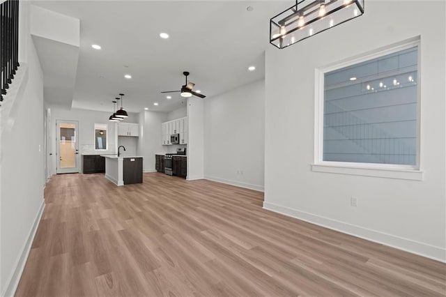 unfurnished living room featuring ceiling fan, sink, and light hardwood / wood-style flooring