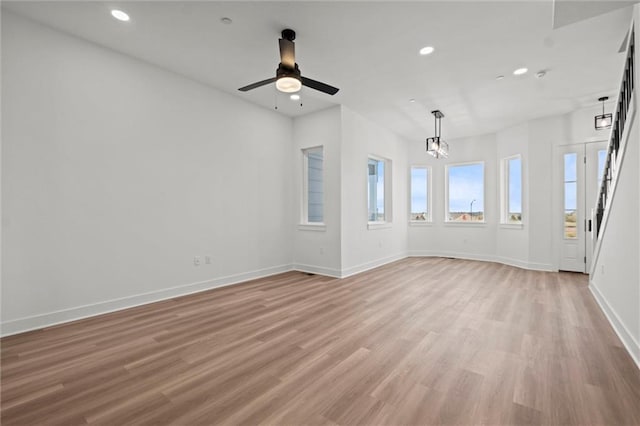 spare room featuring ceiling fan with notable chandelier and light hardwood / wood-style flooring