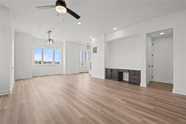 unfurnished living room featuring light wood-type flooring and ceiling fan with notable chandelier