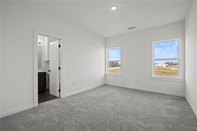 unfurnished bedroom with connected bathroom and dark carpet