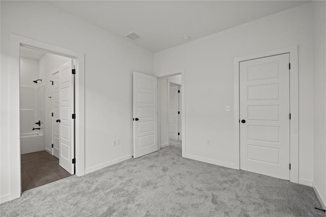 unfurnished bedroom featuring ensuite bath and light colored carpet