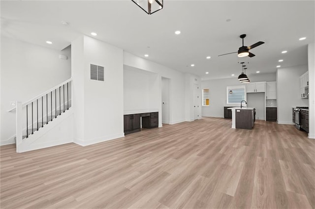 unfurnished living room with light hardwood / wood-style floors, ceiling fan, and sink