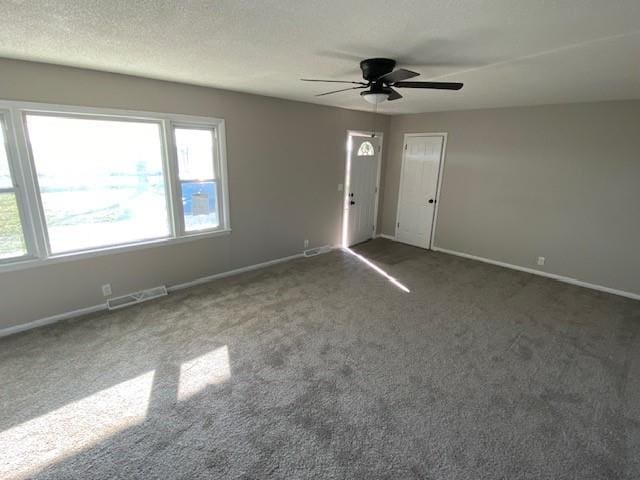 carpeted spare room with a wealth of natural light, ceiling fan, and a textured ceiling