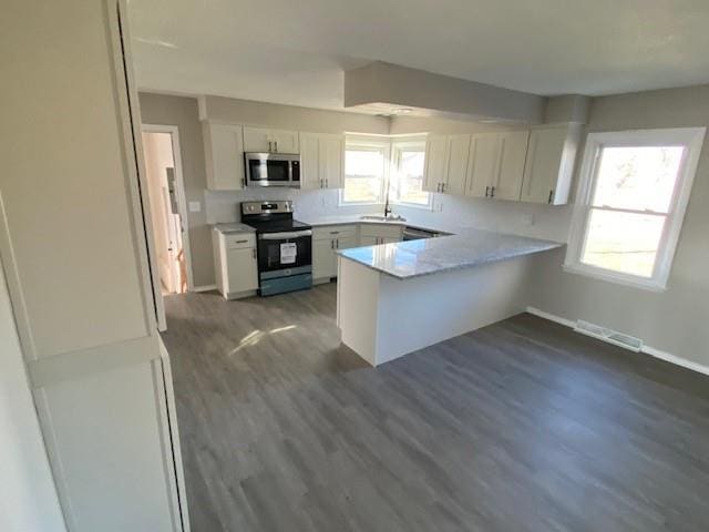 kitchen featuring stainless steel appliances, white cabinets, dark hardwood / wood-style floors, kitchen peninsula, and sink