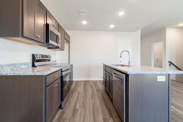 kitchen featuring an island with sink, appliances with stainless steel finishes, sink, and dark brown cabinets