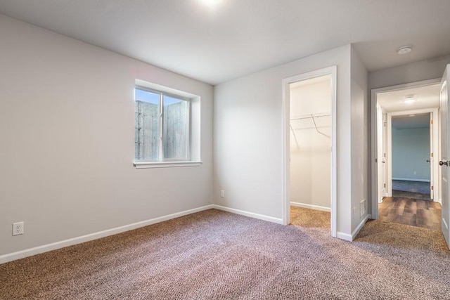 unfurnished bedroom with a closet, a spacious closet, and carpet