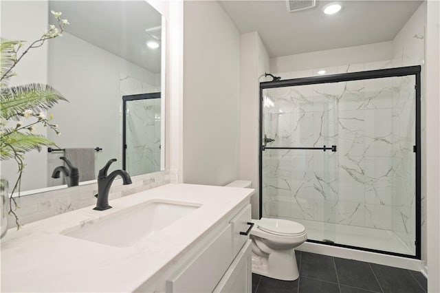 bathroom with vanity with extensive cabinet space, a shower with shower door, toilet, and tile floors