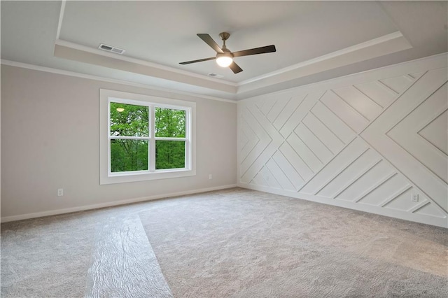 spare room with carpet flooring, crown molding, ceiling fan, and a tray ceiling