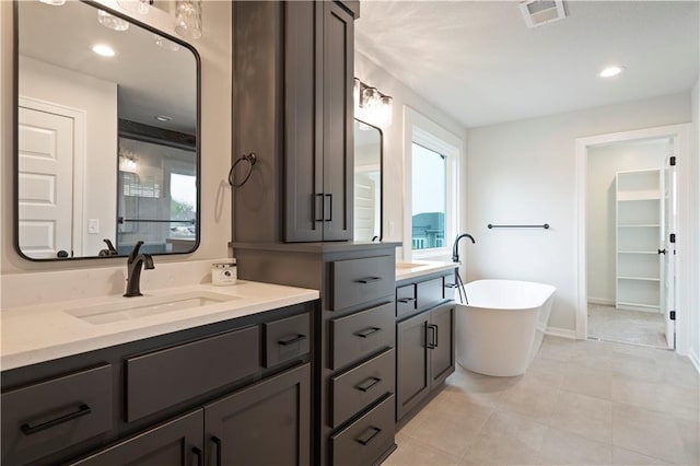 bathroom featuring a washtub, a healthy amount of sunlight, tile flooring, and vanity