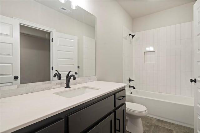 full bathroom featuring tile flooring, vanity, tiled shower / bath combo, and toilet