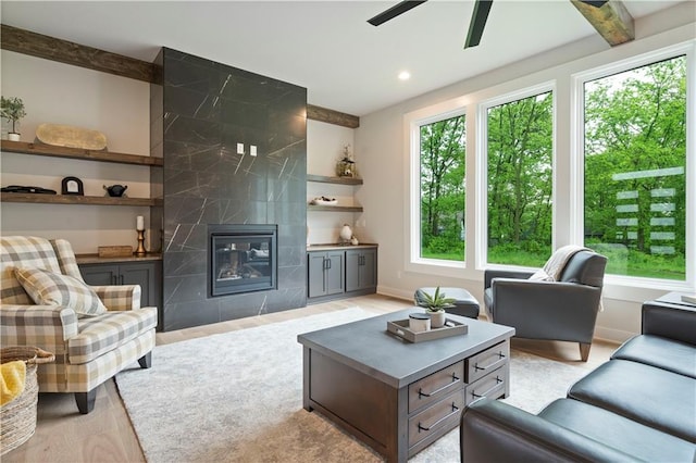 living room featuring a healthy amount of sunlight, a tiled fireplace, and ceiling fan