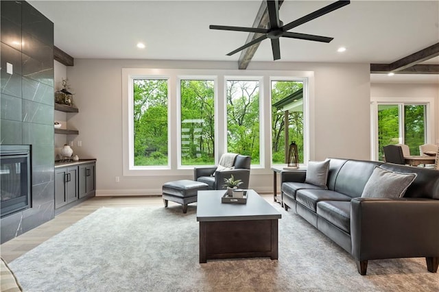 living room featuring ceiling fan, a healthy amount of sunlight, and a fireplace