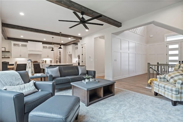 living room with beamed ceiling, ceiling fan, and light hardwood / wood-style floors