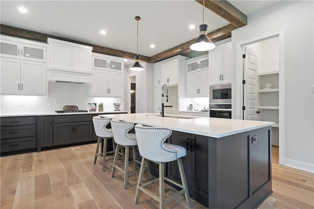 kitchen with beamed ceiling, white cabinetry, gray cabinets, light hardwood / wood-style flooring, and black oven