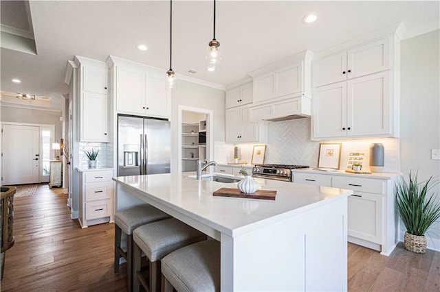 kitchen featuring pendant lighting, a kitchen island with sink, sink, appliances with stainless steel finishes, and white cabinetry