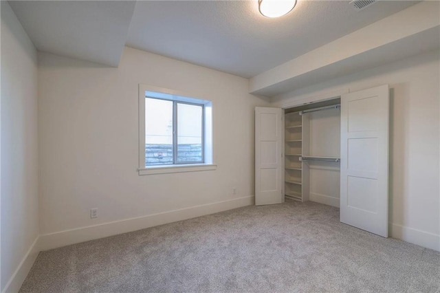 unfurnished bedroom with a closet and light colored carpet