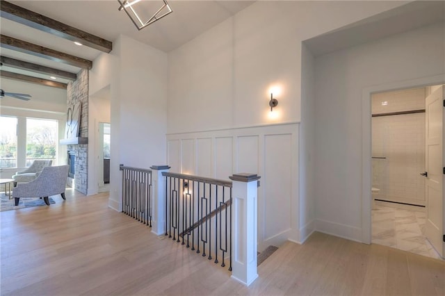 hall with light wood-type flooring and beamed ceiling