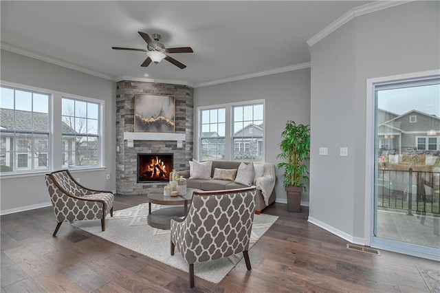 living room featuring ornamental molding, a stone fireplace, and dark wood-type flooring