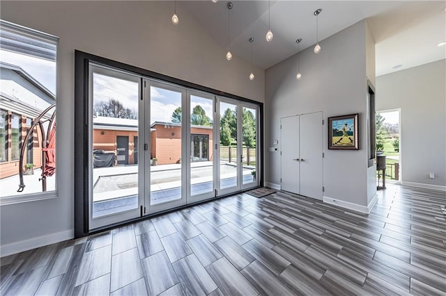 unfurnished living room with a healthy amount of sunlight, dark hardwood / wood-style flooring, and high vaulted ceiling