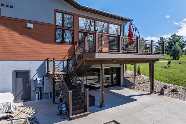 back of house featuring a wooden deck, a lawn, and a patio