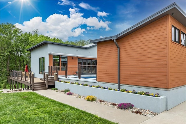 view of side of home featuring a wooden deck and a yard