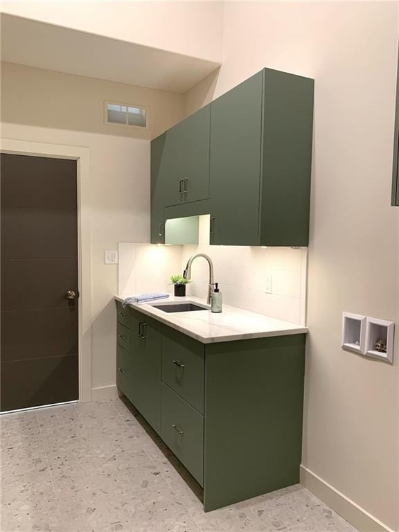 kitchen with sink, green cabinets, backsplash, and light tile floors