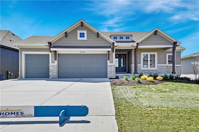 craftsman-style house featuring an attached garage, stone siding, driveway, and a front lawn