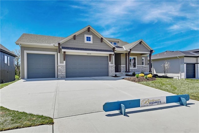 craftsman-style house with driveway, a garage, stucco siding, and stone siding