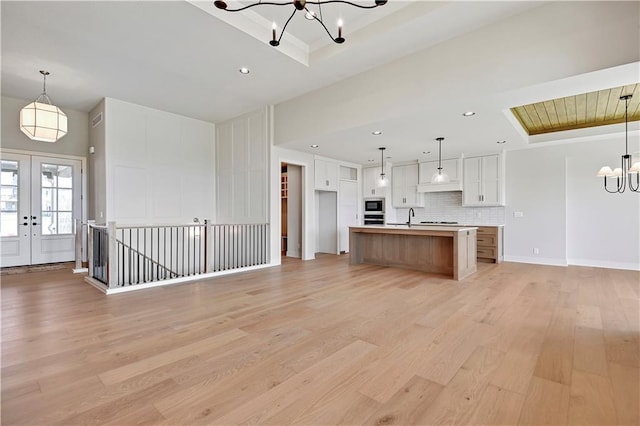 kitchen with tasteful backsplash, an inviting chandelier, open floor plan, light wood finished floors, and built in microwave