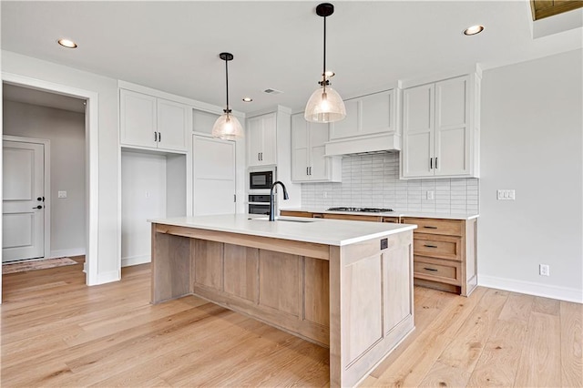 kitchen featuring tasteful backsplash, gas cooktop, light countertops, a sink, and built in microwave