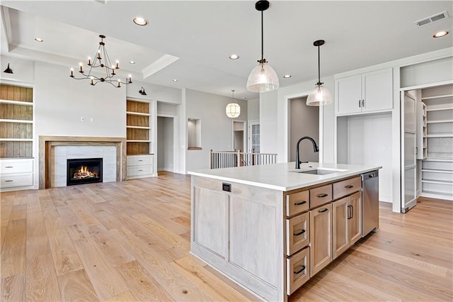 kitchen featuring visible vents, decorative light fixtures, a sink, light wood finished floors, and stainless steel dishwasher