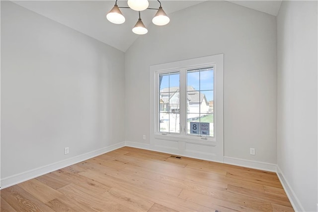 unfurnished room with light wood finished floors, baseboards, and vaulted ceiling