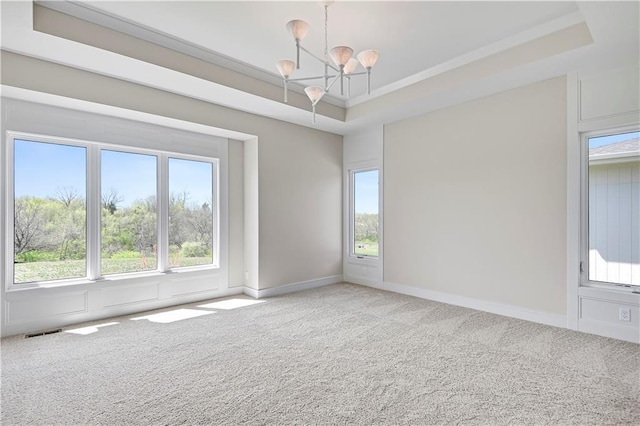 carpeted empty room with a chandelier, visible vents, a tray ceiling, and baseboards