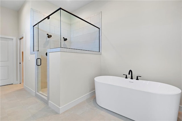 bathroom with baseboards, a freestanding bath, and a stall shower