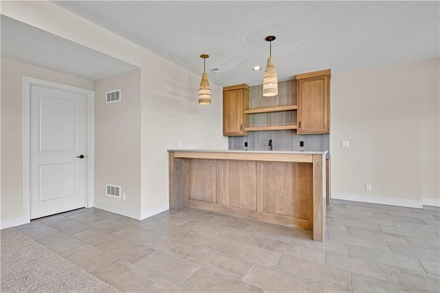 kitchen featuring visible vents, baseboards, light countertops, and hanging light fixtures
