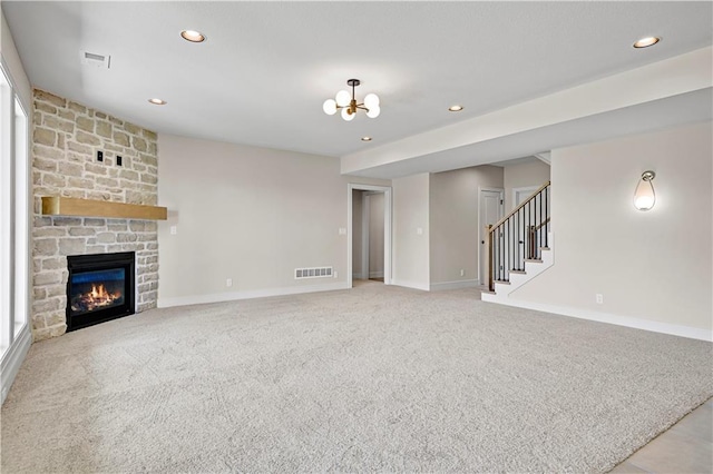 unfurnished living room featuring visible vents, a stone fireplace, recessed lighting, stairs, and light carpet