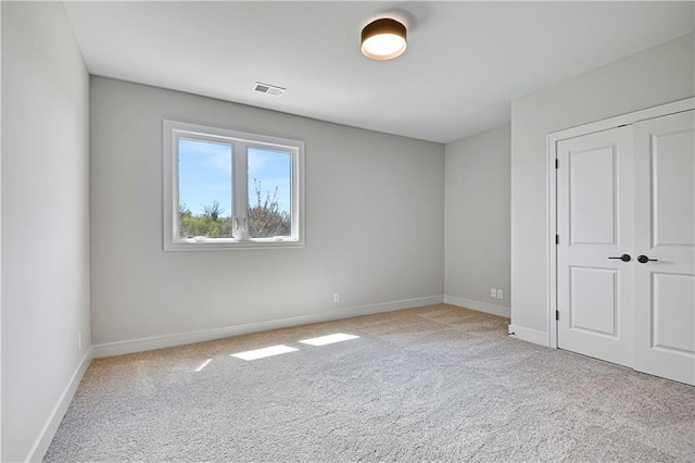 carpeted spare room with visible vents and baseboards