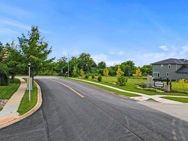 view of street featuring traffic signs, sidewalks, street lights, and curbs