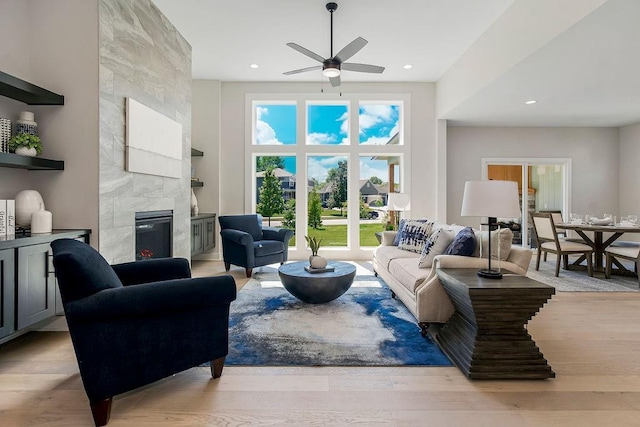 living room with a fireplace, light hardwood / wood-style floors, and ceiling fan